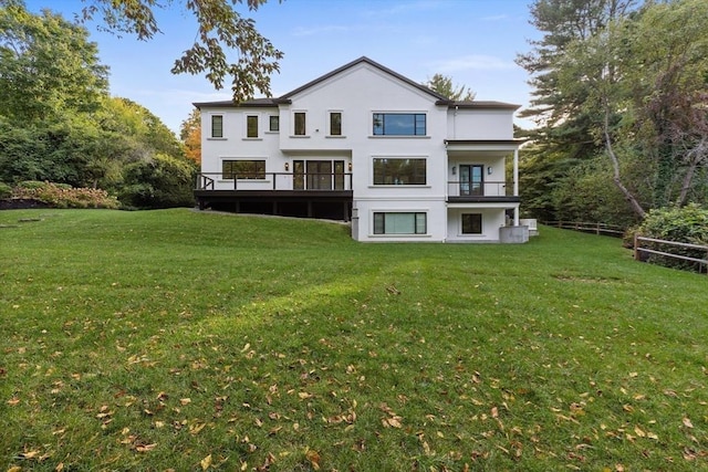 back of property with a balcony, a lawn, and stucco siding