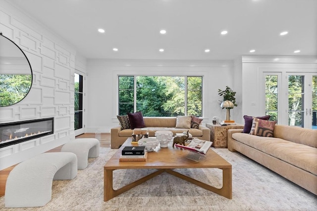 living room with light wood-type flooring, recessed lighting, crown molding, and a glass covered fireplace