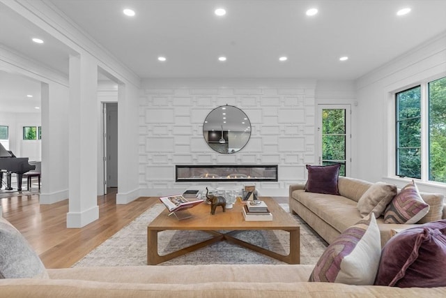 living area with a stone fireplace, recessed lighting, and light wood-style floors