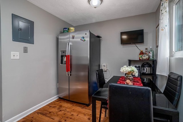 dining space with hardwood / wood-style flooring, electric panel, and a textured ceiling