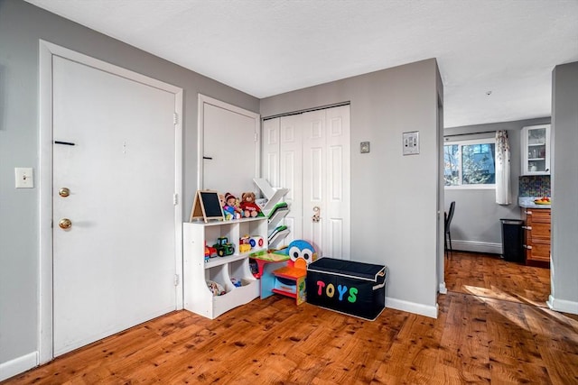 playroom featuring hardwood / wood-style flooring and a baseboard heating unit