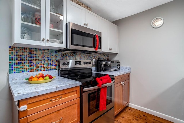 kitchen featuring decorative backsplash, light hardwood / wood-style flooring, stainless steel appliances, and white cabinets