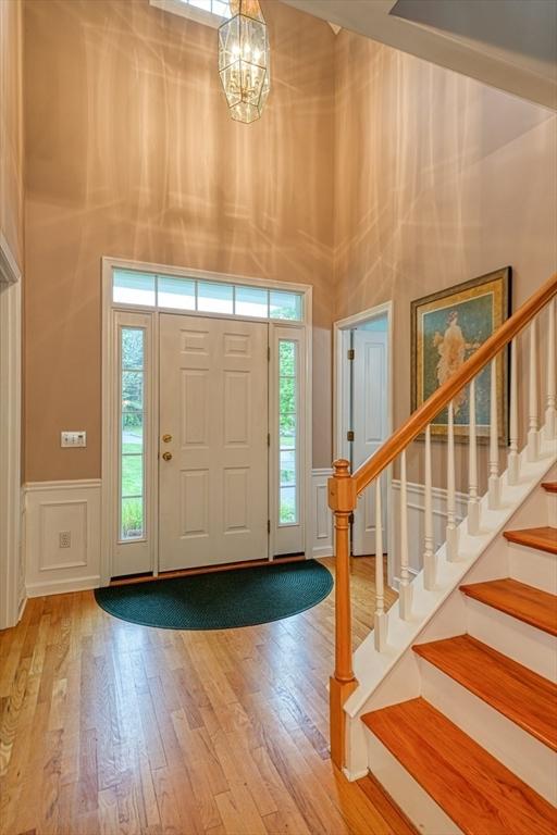 106 Willow Brook Dr Unit 106, Wayland, MA 01778 - entrance foyer featuring a towering ceiling, a decorative wall, wood finished floors, a chandelier, and stairs