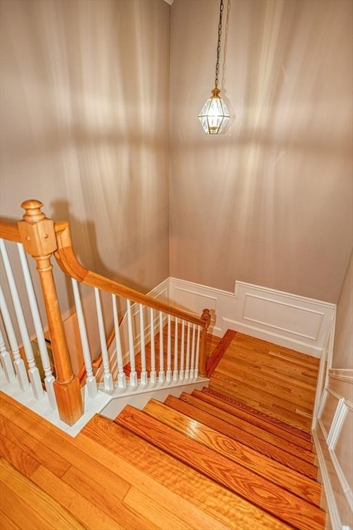 106 Willow Brook Dr Unit 106, Wayland, MA 01778 - stairs featuring a decorative wall, wood finished floors, and wainscoting