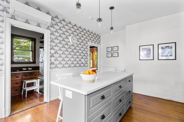 30 Welles Ave Unit 2, Boston, MA 02124 - kitchen featuring gray cabinets, a wall mounted AC, light countertops, wainscoting, and wood finished floors
