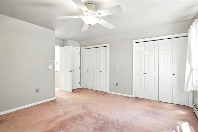 unfurnished bedroom featuring a ceiling fan, light colored carpet, baseboards, two closets, and a baseboard heating unit