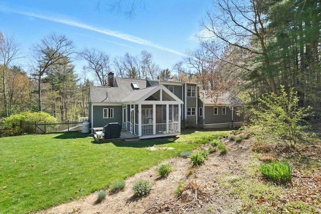 rear view of property with a sunroom, fence, a yard, and a chimney
