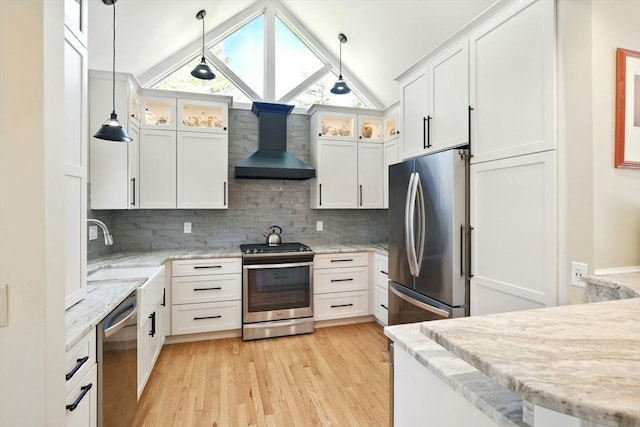kitchen featuring decorative backsplash, wall chimney range hood, light wood-type flooring, a sink, and stainless steel appliances