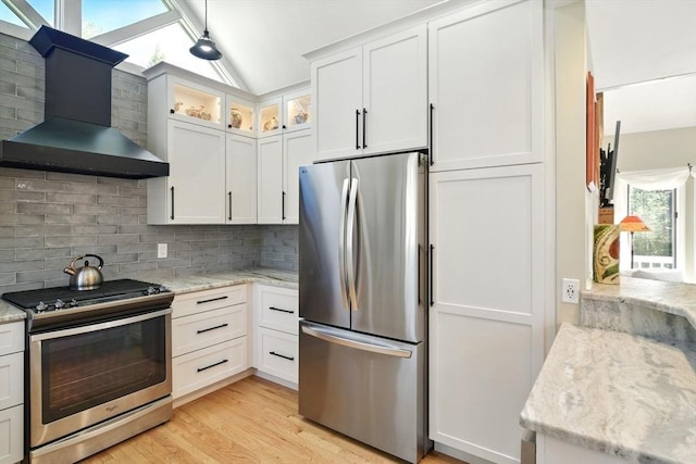 kitchen with light wood-style flooring, wall chimney exhaust hood, stainless steel appliances, lofted ceiling, and tasteful backsplash