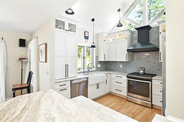 kitchen with white cabinetry, tasteful backsplash, a sink, light wood finished floors, and stainless steel appliances