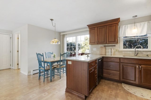 kitchen with backsplash, a peninsula, light wood-style floors, and a sink