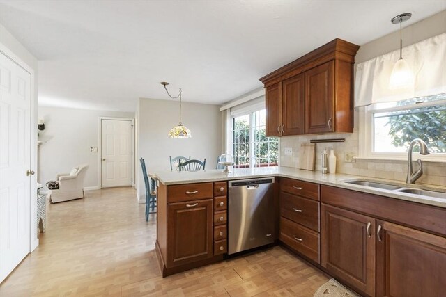 kitchen with a sink, dishwasher, a peninsula, and light countertops