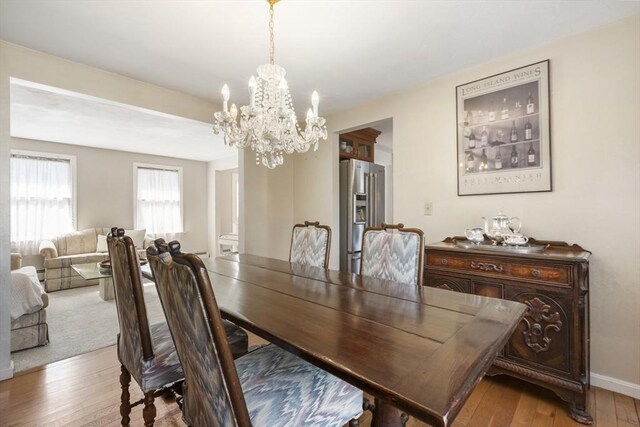 dining space with light wood finished floors, a chandelier, and baseboards