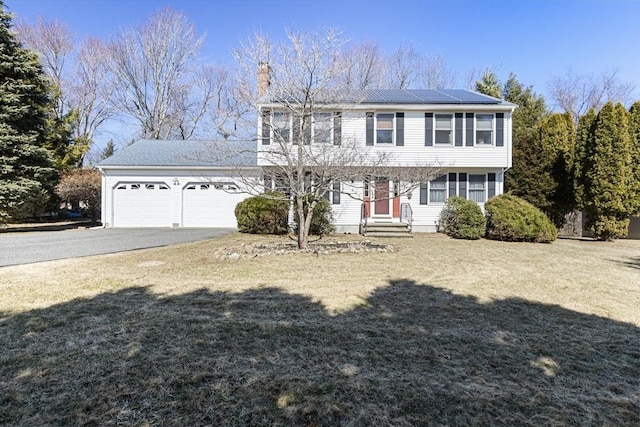 colonial house with a front lawn, driveway, an attached garage, and entry steps