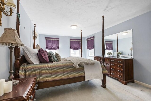 bedroom featuring baseboards, light colored carpet, and a textured ceiling