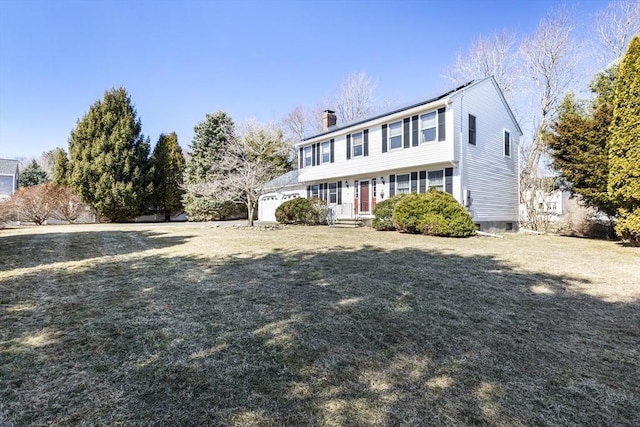 colonial-style house with a front lawn, an attached garage, and a chimney