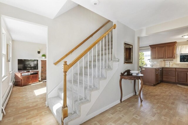 stairs with baseboard heating, baseboards, and wood finished floors