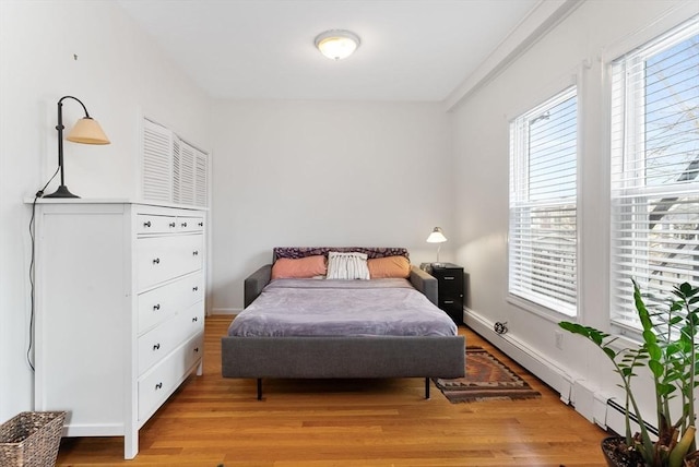 bedroom featuring light wood-type flooring and a baseboard heating unit