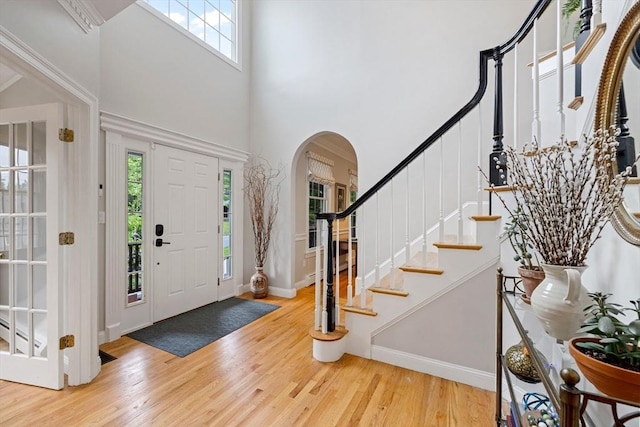 22 Flintlock Rd, Lexington, MA 02420 - entrance foyer featuring a towering ceiling, arched walkways, wood finished floors, and stairs