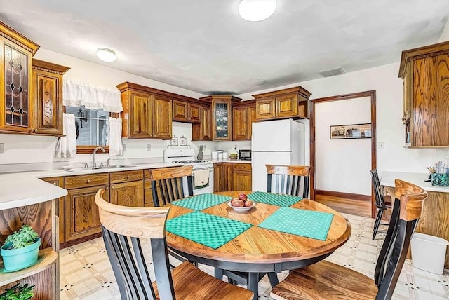 kitchen with light floors, a sink, brown cabinets, and white appliances