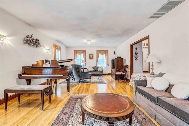 living room featuring visible vents, light wood-style flooring, and baseboards
