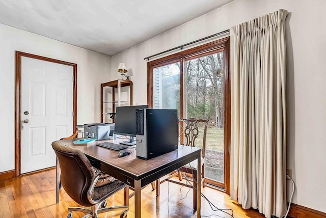 home office with light wood-style flooring and baseboards