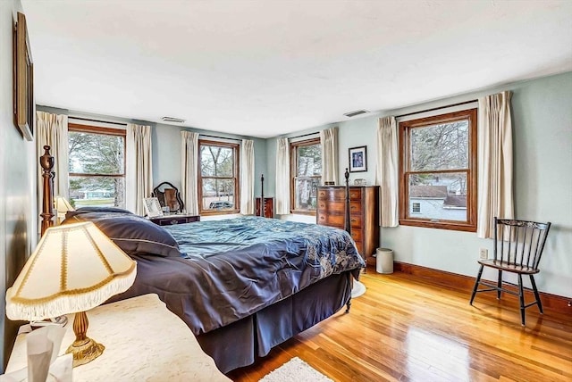 bedroom with visible vents, wood finished floors, and baseboards