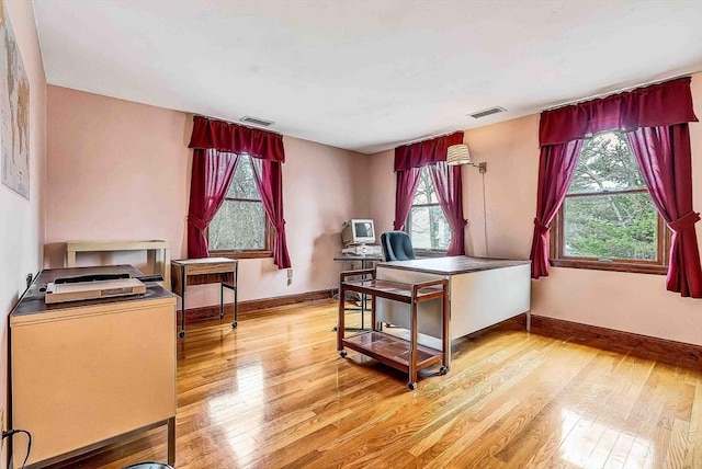 office space with baseboards, visible vents, and light wood-style floors