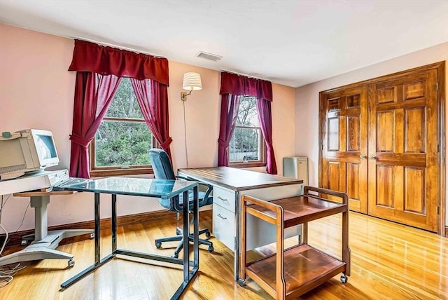 office space with wood finished floors, visible vents, plenty of natural light, and baseboards