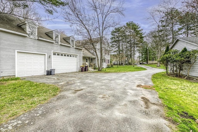 view of side of home featuring a shingled roof, driveway, and a lawn