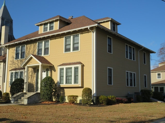 view of front of property with central AC unit and a front lawn