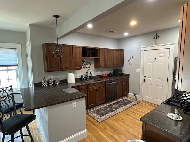 kitchen with dishwasher, sink, kitchen peninsula, decorative light fixtures, and a kitchen bar