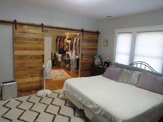 bedroom featuring light wood-type flooring, a closet, and a barn door