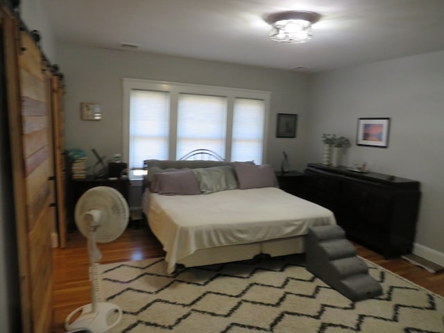 bedroom with a barn door and hardwood / wood-style flooring