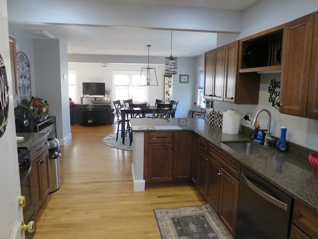 kitchen with sink, dishwasher, kitchen peninsula, decorative light fixtures, and light wood-type flooring