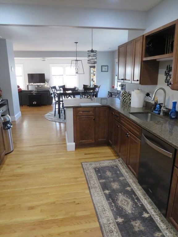 kitchen with sink, hanging light fixtures, light hardwood / wood-style flooring, stainless steel dishwasher, and kitchen peninsula