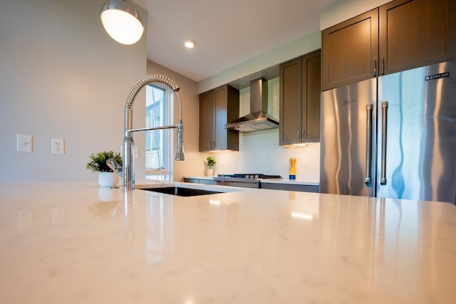 kitchen with appliances with stainless steel finishes, sink, backsplash, and wall chimney exhaust hood