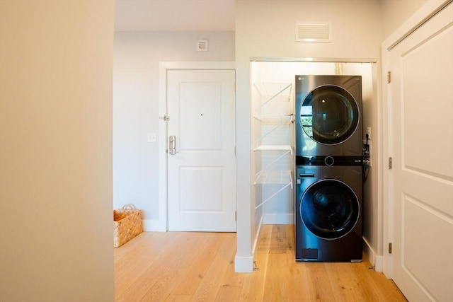 laundry room with stacked washer / dryer and light hardwood / wood-style floors