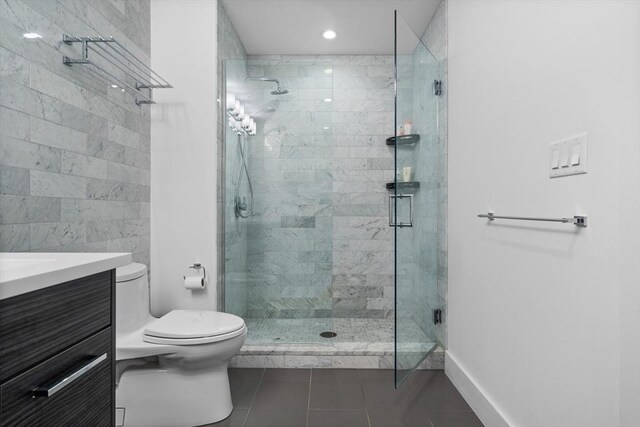 bathroom featuring tile patterned flooring, toilet, walk in shower, and vanity