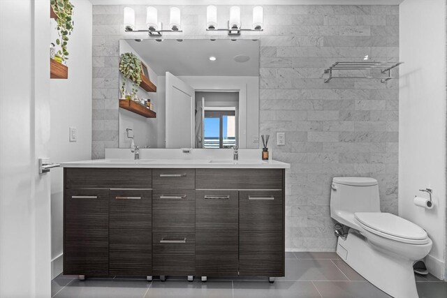 bathroom with vanity, tile patterned flooring, tile walls, toilet, and a shower