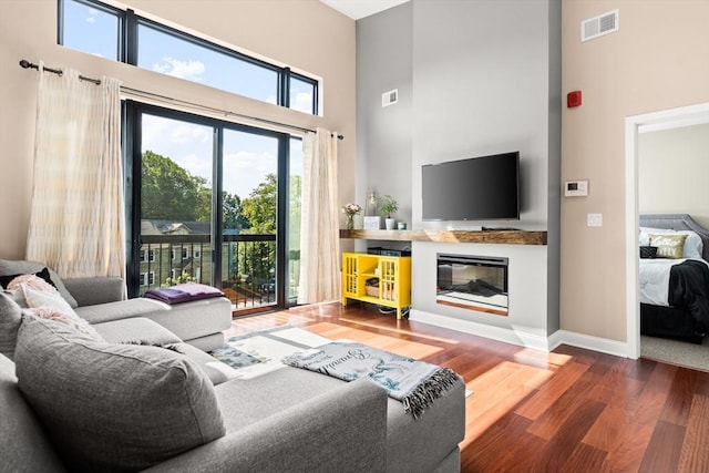 1 Brook Rd Unit 306, Quincy, MA 02169 - living area featuring a high ceiling, wood finished floors, baseboards, and a glass covered fireplace