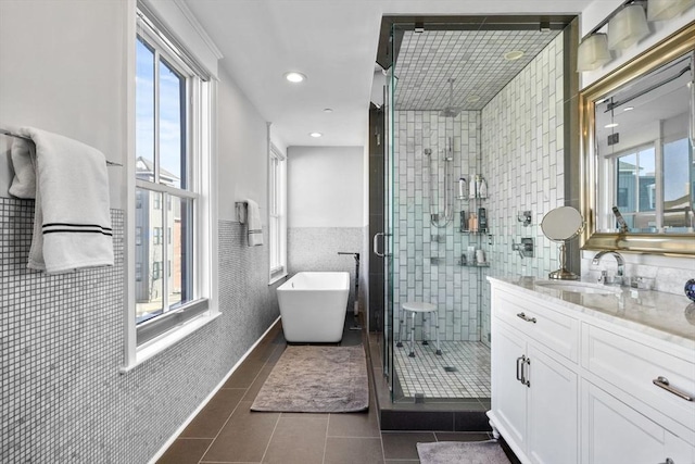 bathroom with a freestanding bath, wainscoting, a shower stall, vanity, and tile patterned floors