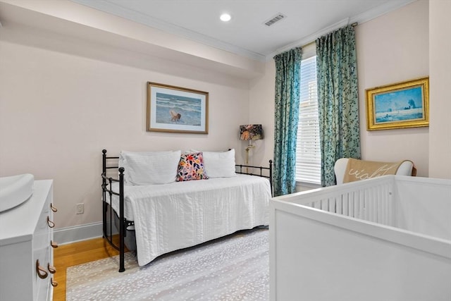 bedroom with wood finished floors, visible vents, crown molding, and multiple windows