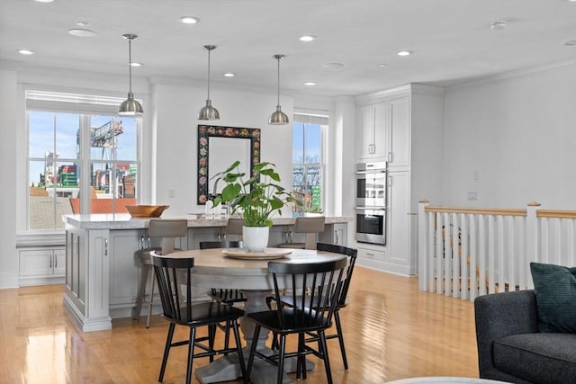 dining space featuring a healthy amount of sunlight, light wood-style floors, and crown molding