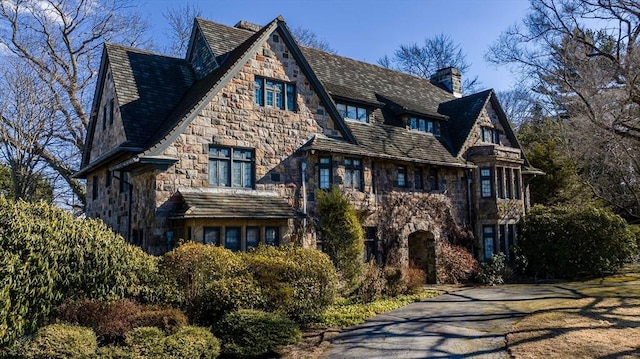 exterior space featuring stone siding and a chimney