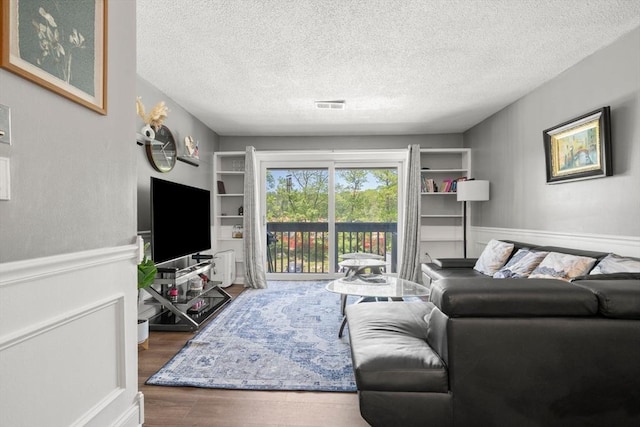 2012 Franklin Crossing Rd Unit 2012, Franklin, MA 02038 - living area with a textured ceiling, wood finished floors, and wainscoting