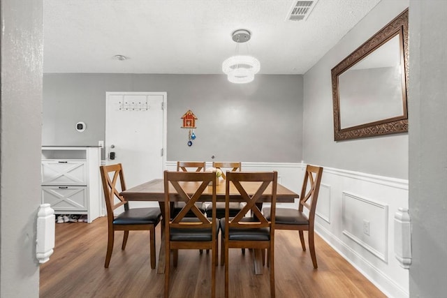 2012 Franklin Crossing Rd Unit 2012, Franklin, MA 02038 - dining area with wood finished floors, a wainscoted wall, a chandelier, and a textured ceiling