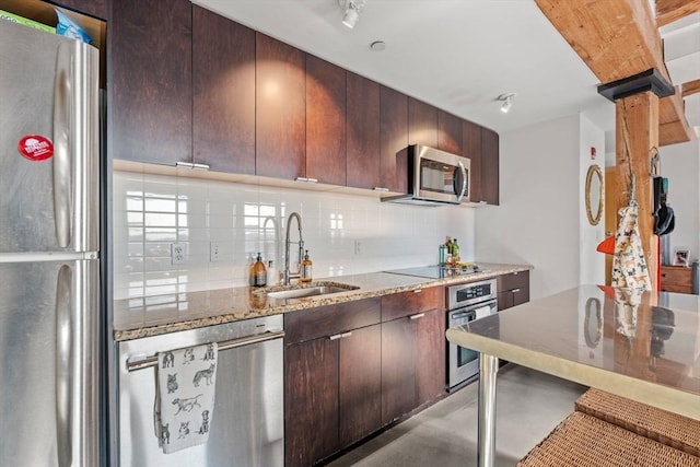 kitchen featuring backsplash, sink, light stone countertops, appliances with stainless steel finishes, and dark brown cabinets