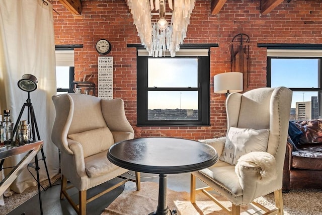 sitting room with beam ceiling, a healthy amount of sunlight, and brick wall