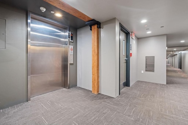 corridor with light colored carpet and elevator